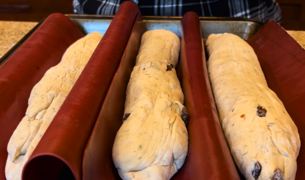 The herb stuffing bread dough baguettes separated by red silicone mats on a baking sheet.