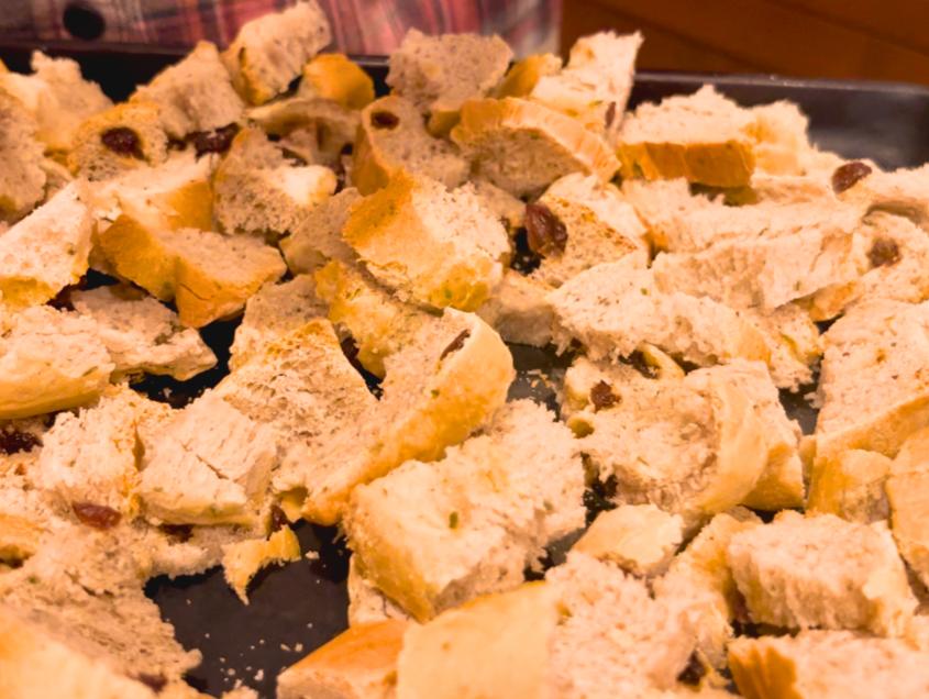 A baking sheet with ripped up chunks of herb stuffing bread drying