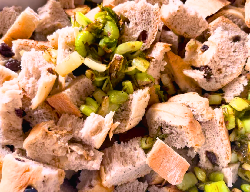 A crockpot full of dried herb stuffing bread chunks and fried celery and onions on top.
