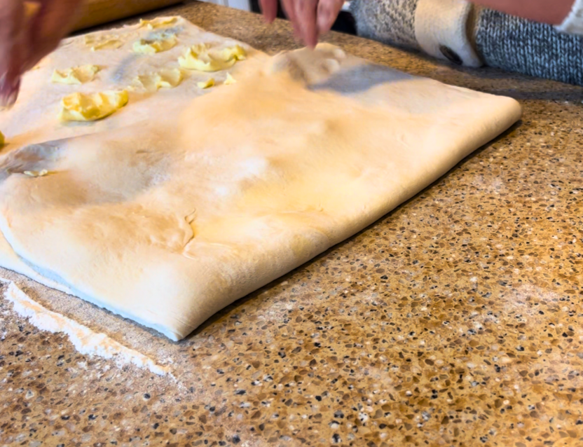 A woman folding Scottish butter roll dough.
