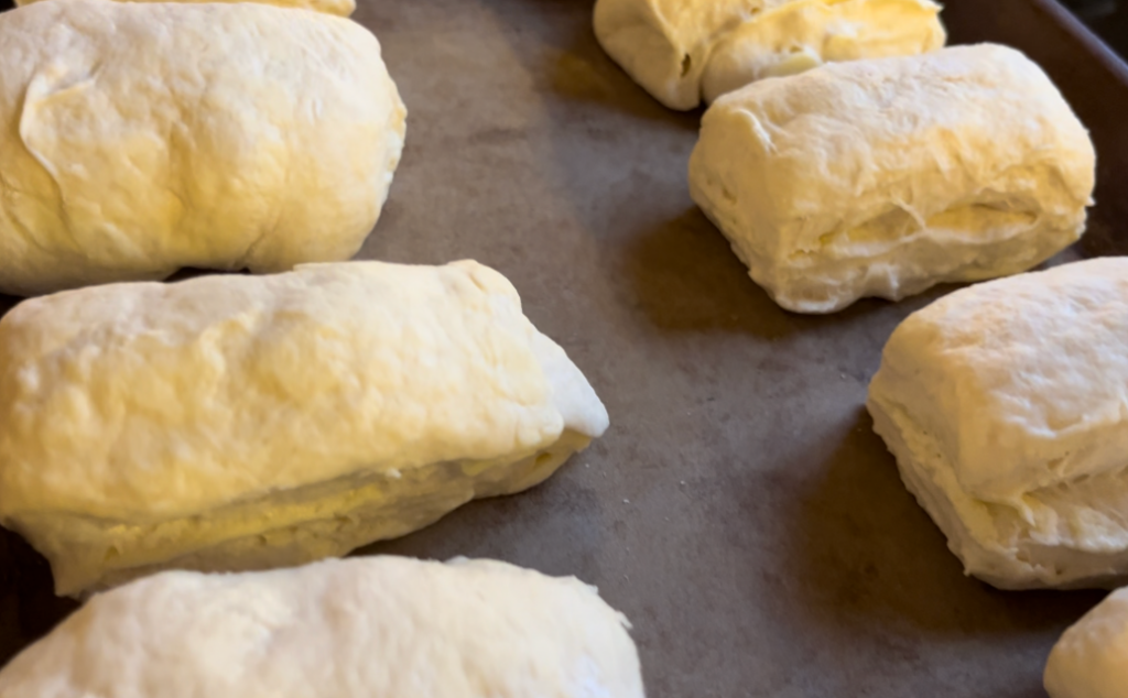 A tray of risen Scottish butter rolls, unbaked, on a cookie sheet