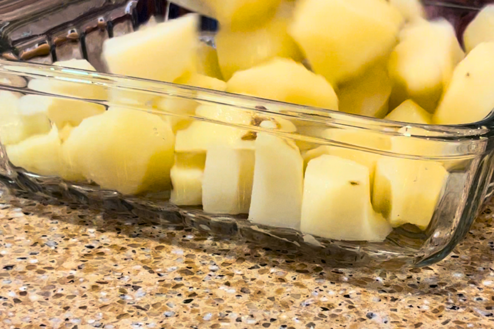 A square glass casserole dish with cut, peeled and cooked potatoes.