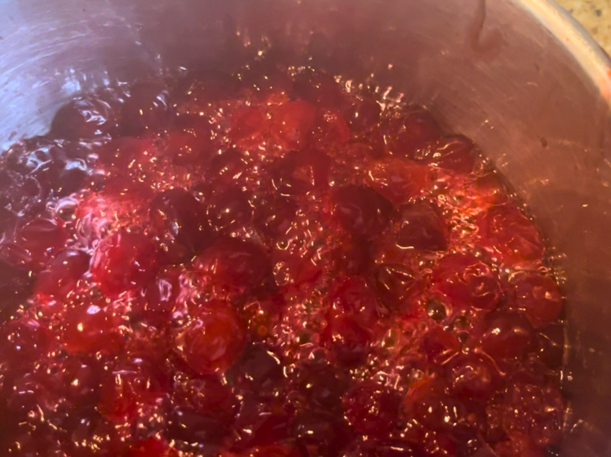 cranberry sauce simmering in a metal sauce pot