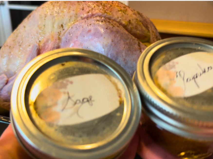 A woman holding sage and paprika spice jars. A turkey in a roasting pan in the background.