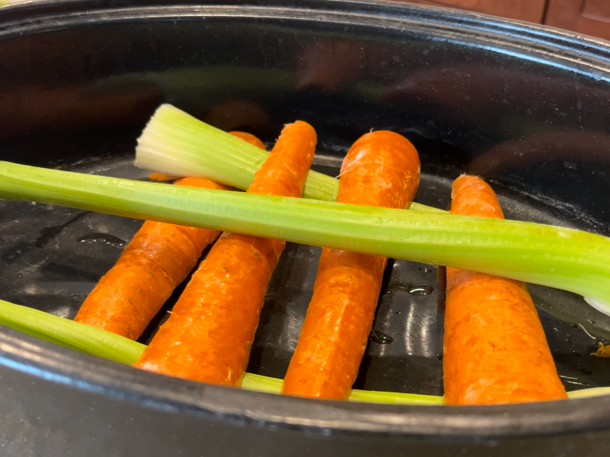 celery ribs and carrot sticks in a roasting pan