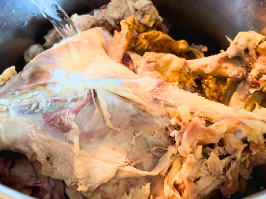 Water pouring onto a turkey carcass in a large stockpot