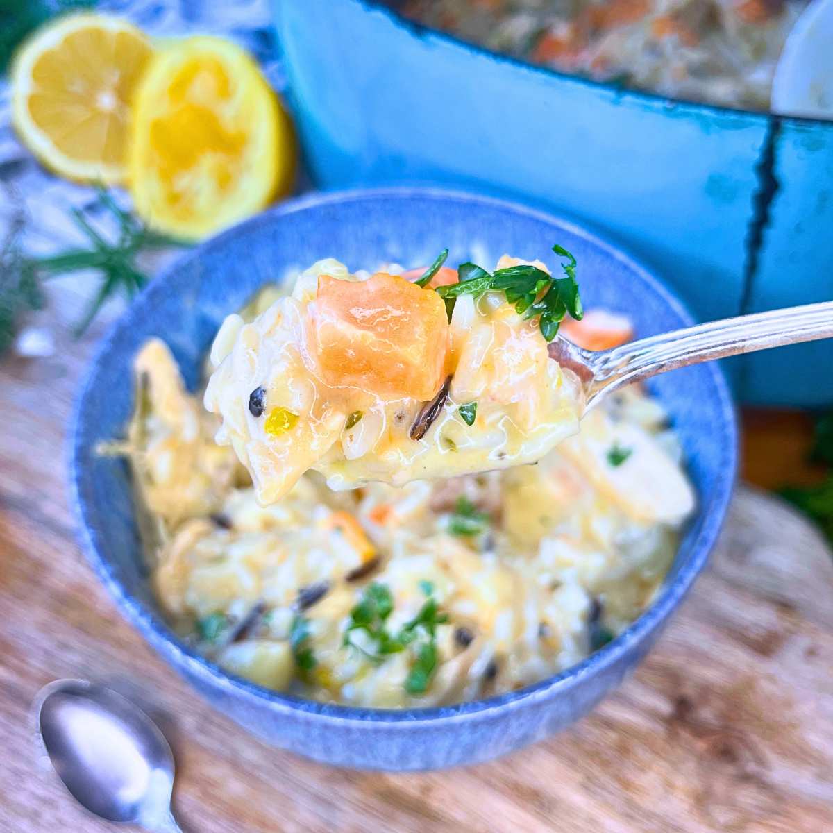 A blue bowl filled with turkey and rice soup. There is a blue pot in the background with more soup.