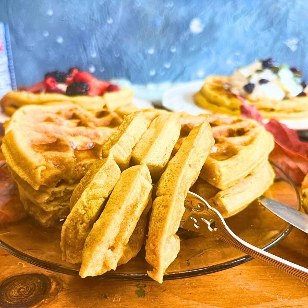 A few stacks of pumpkin waffles. There is a slice out of one stack. It is pierced with a fork.