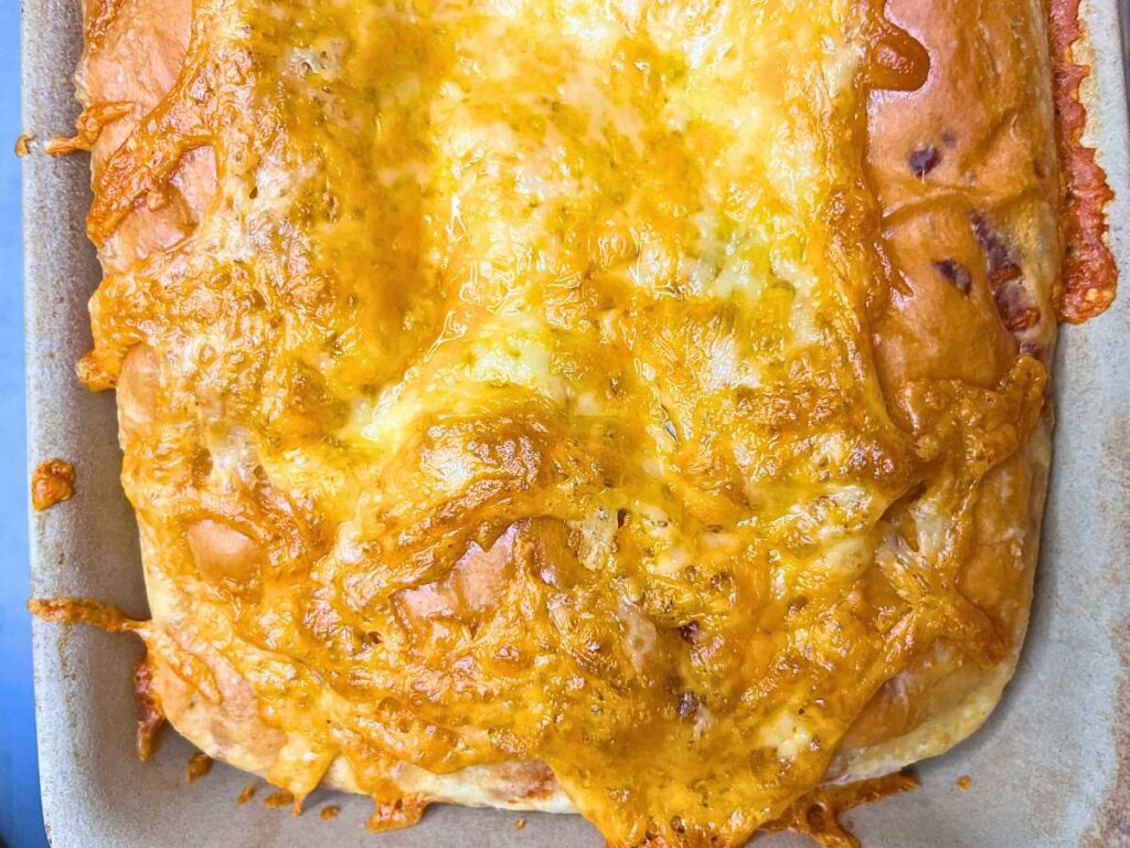 A close up look at the top of a cheese bread loaf.