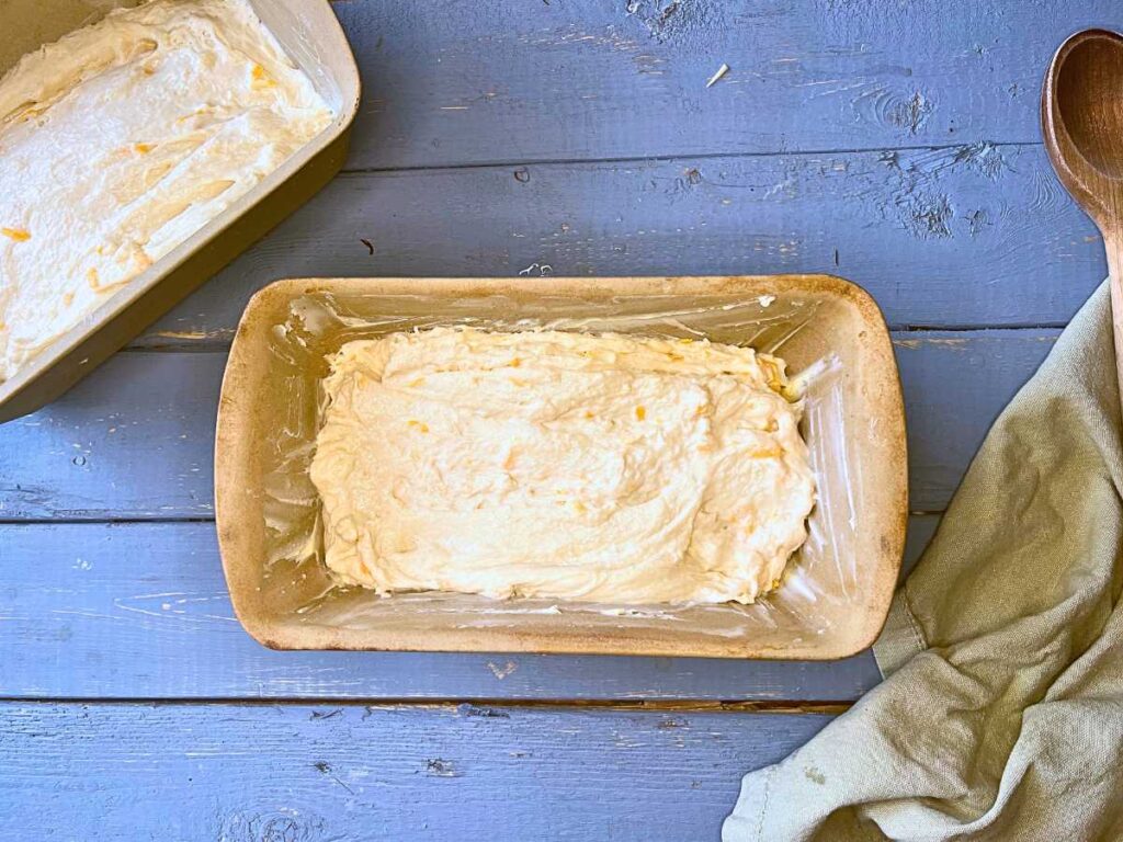 Cheese bread dough is spread into two loaf pans.