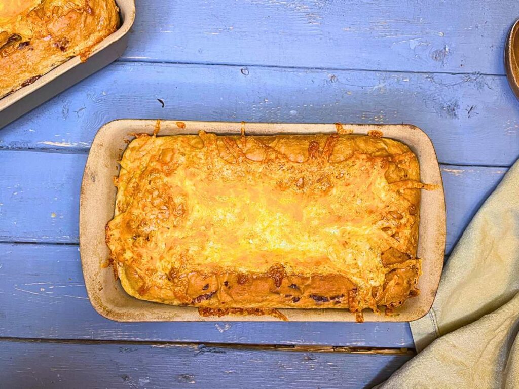 A baked cheese bread loaf in a stone loaf pan.