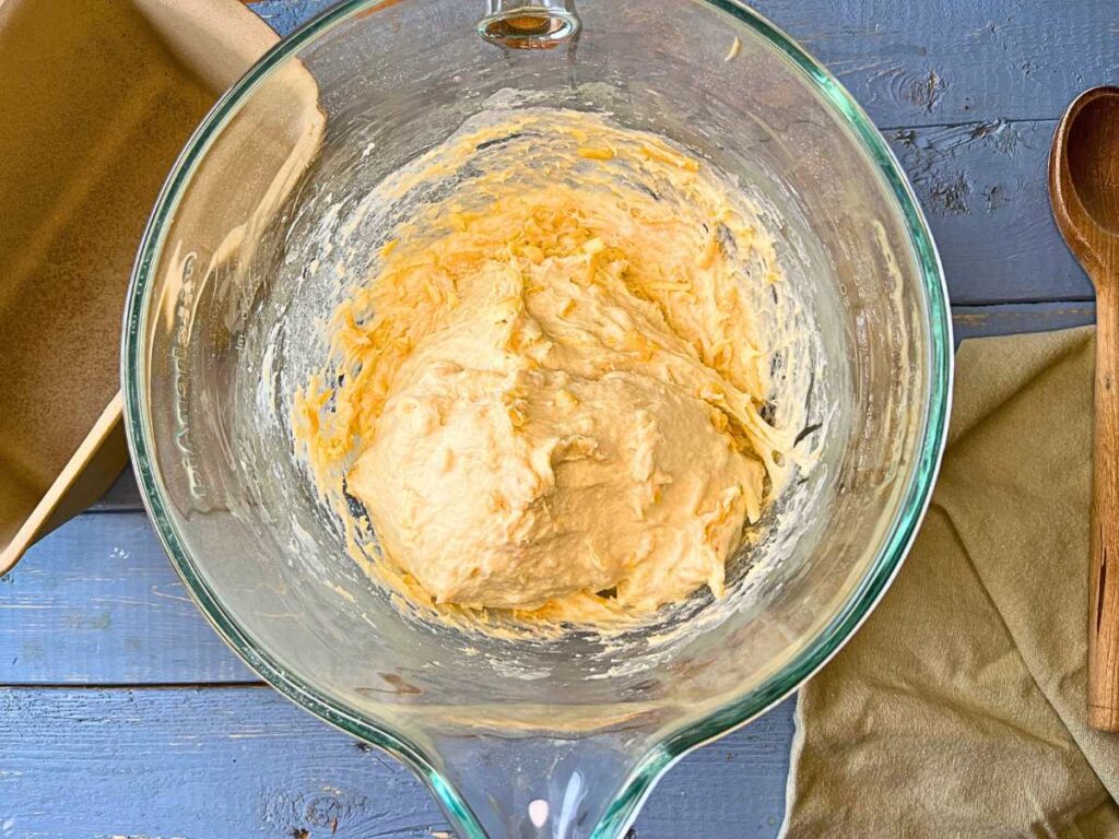 A glass bowl with cheese bread dough inside.