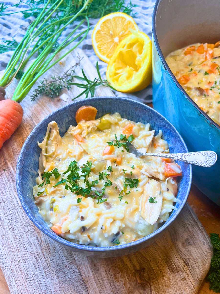 A blue bowl with turkey and rice soup inside. There is more in a blue pot off to the side.