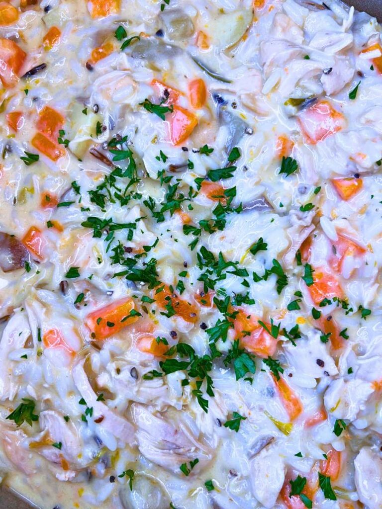 A close up look at turkey and rice cream soup. There is fresh parsley on top.