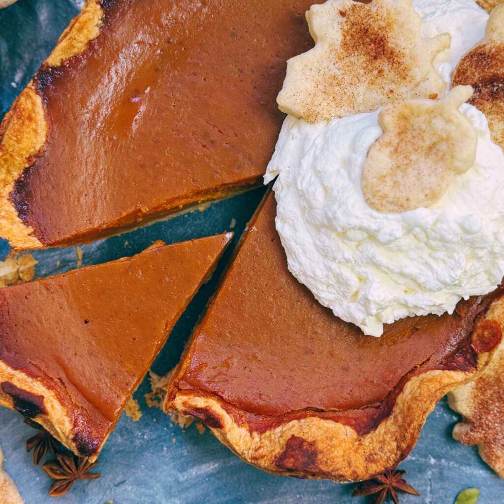 A homemade pumpkin pie with one slice that has been cut.