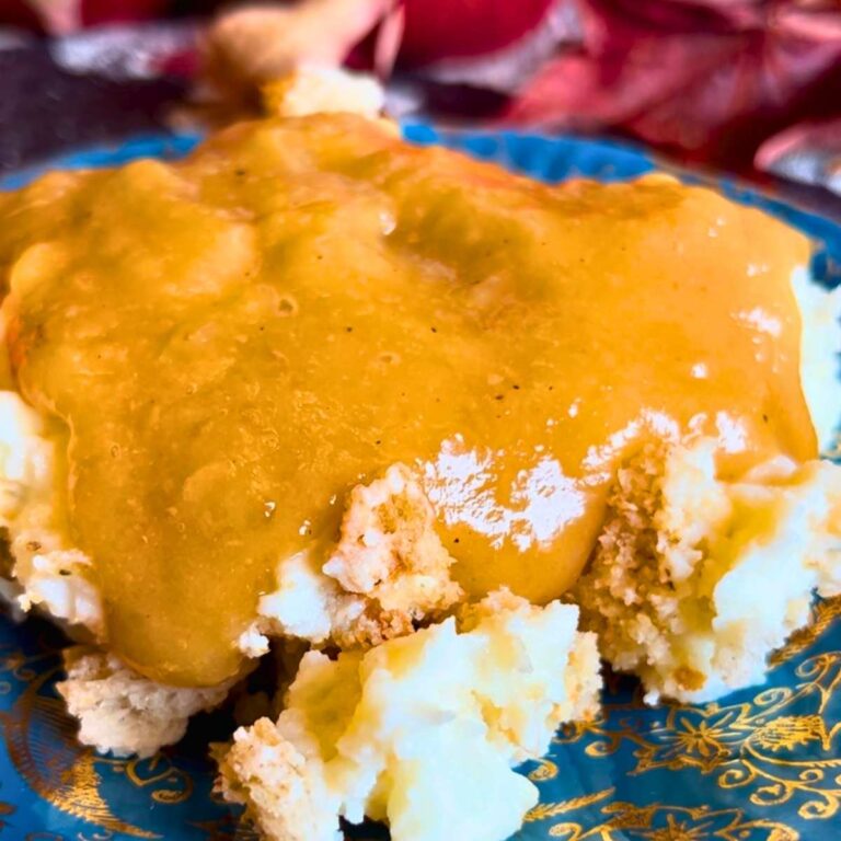 A blue and gold plate with a scoop of mashed potatoes. There is gravy on top.