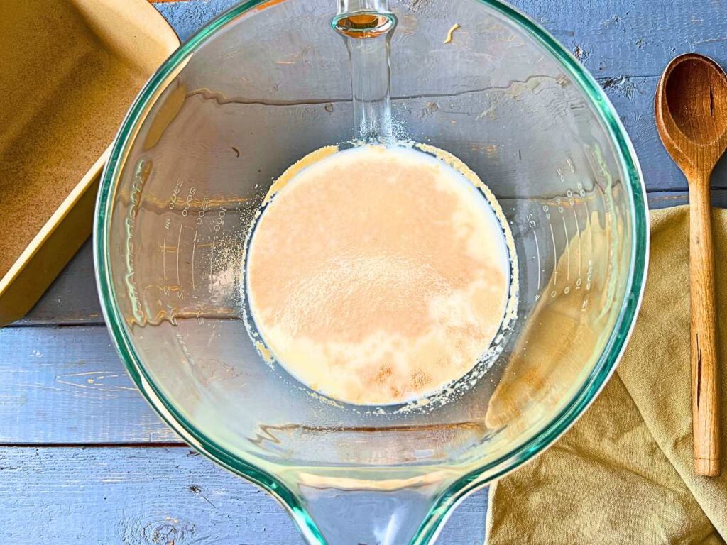 A glass bowl with milk and yeast inside.