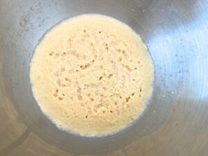 Softened foamy yeast in a metal bowl.