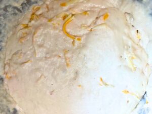 Risen cheese bread dough in a metal bowl.