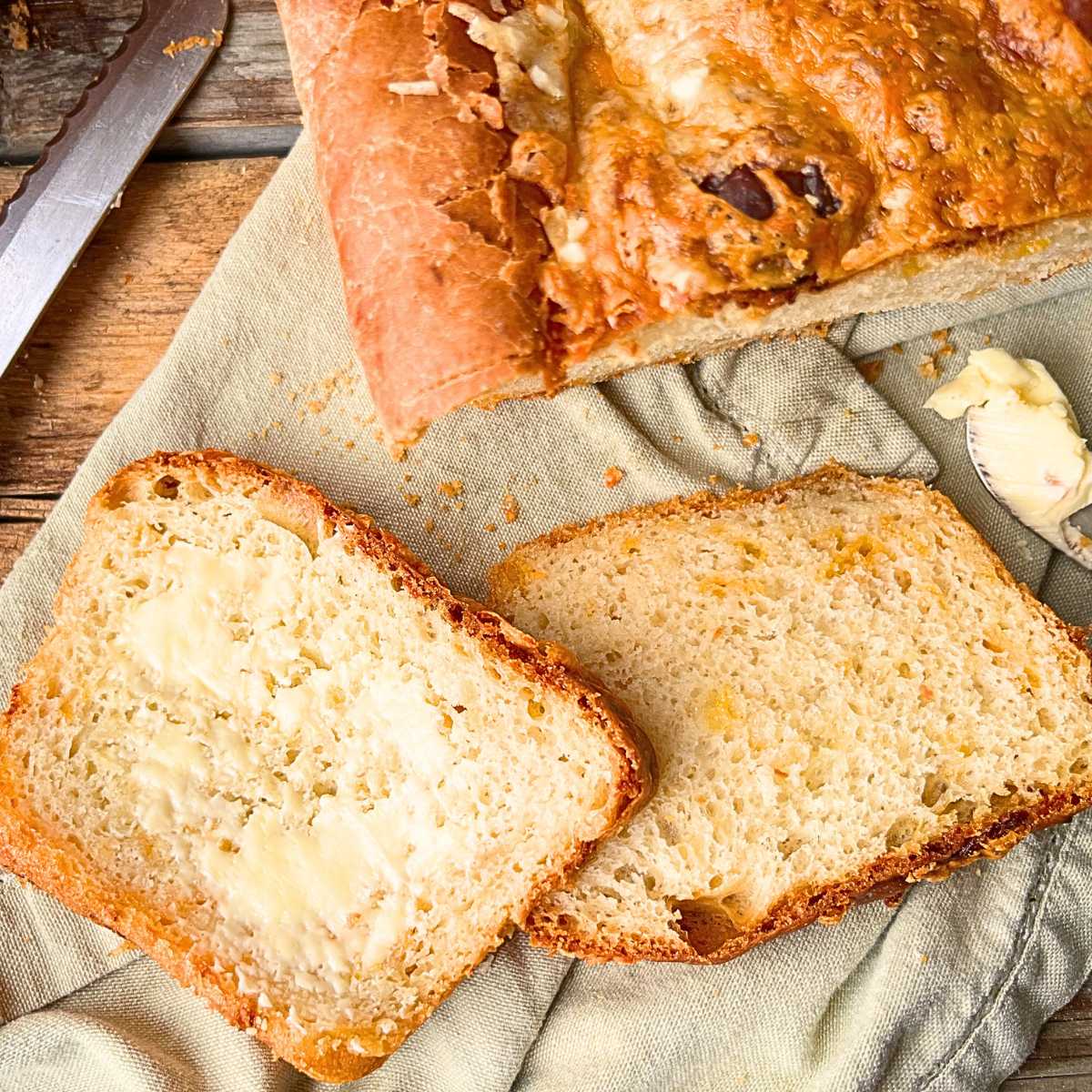 A loaf of cheese bread. There are two slices in front.