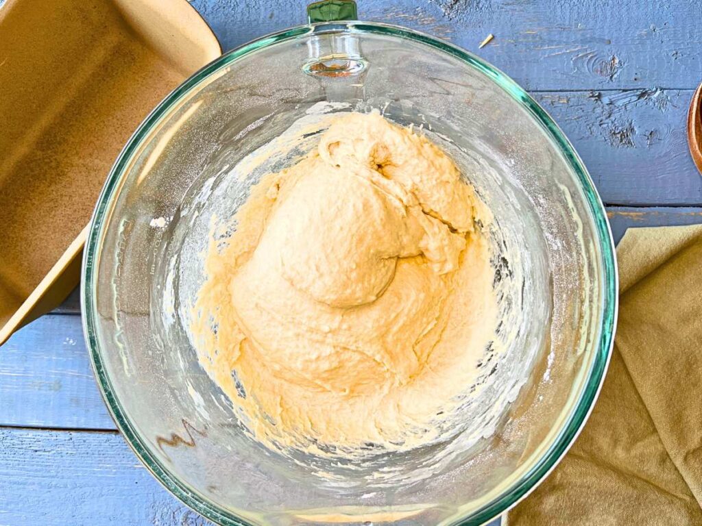 A glass bowl with bread dough inside.