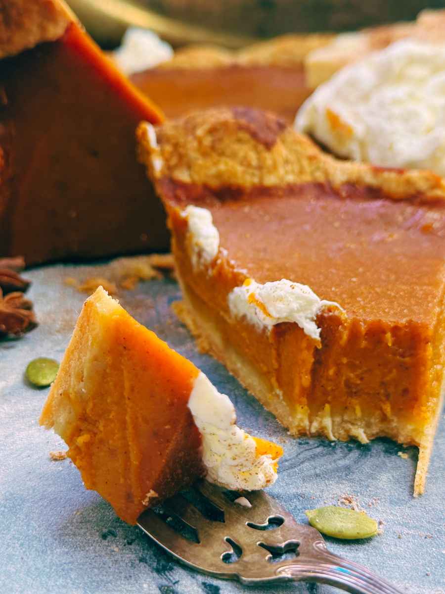 A slice of pumpkin pie with a forkful removed at the front.