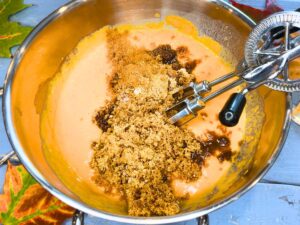 A metal bowl with pumpkin pie filling, brown sugar, and spices.