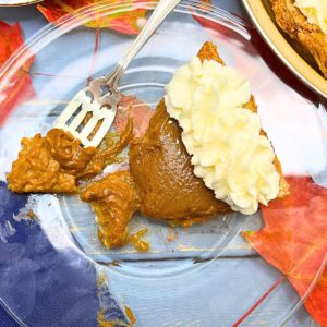 There is a piece of pumpkin pie with whipped cream pipped on top.