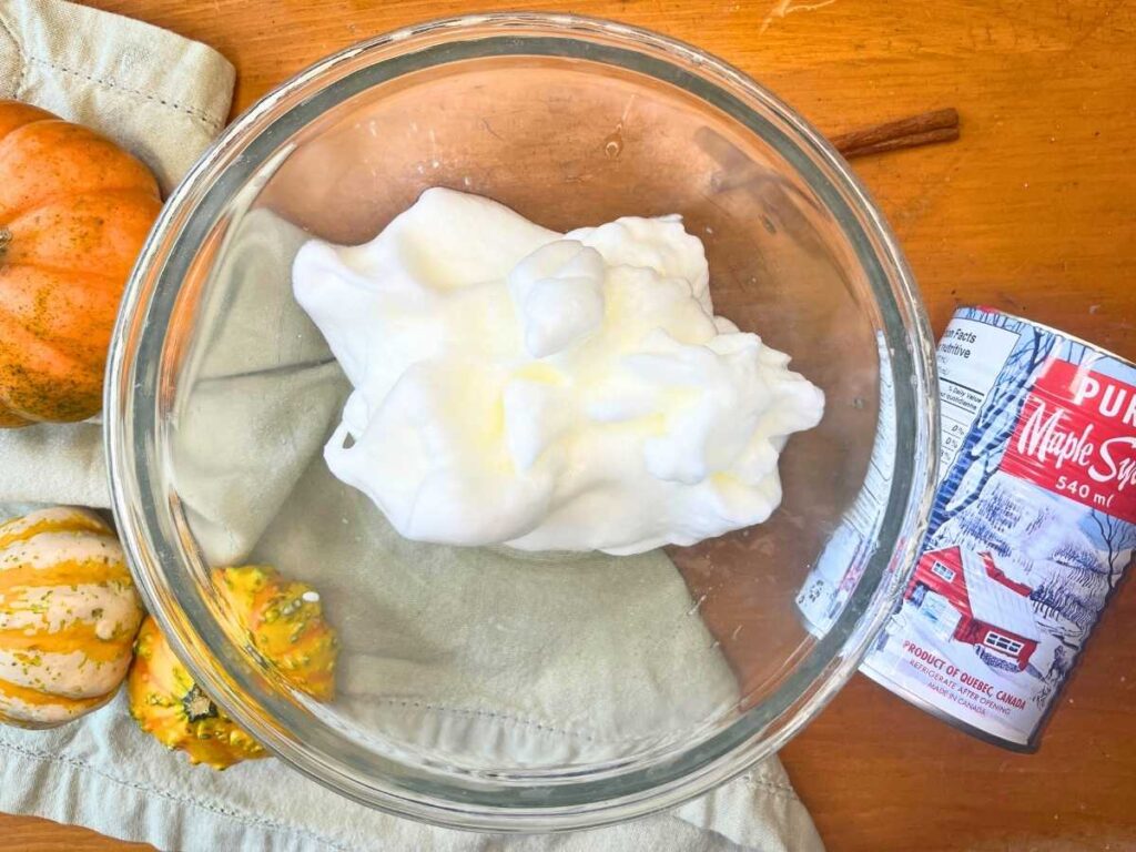 A glass bowl with whipped egg whites inside.