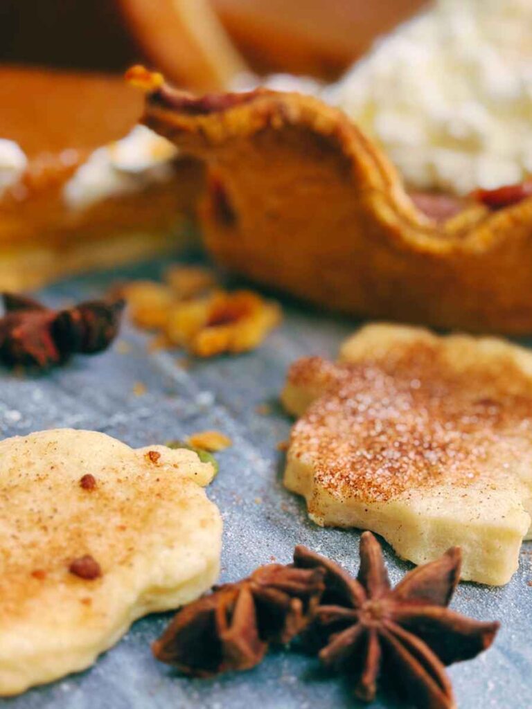 Some pie crust cutouts and a pumpkin pie in the background.
