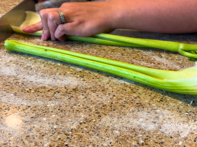 A woman cutting two ribs of celery