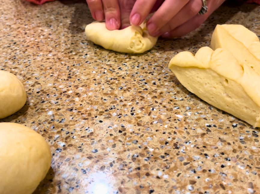 Woman folding and shaping dinner roll dough