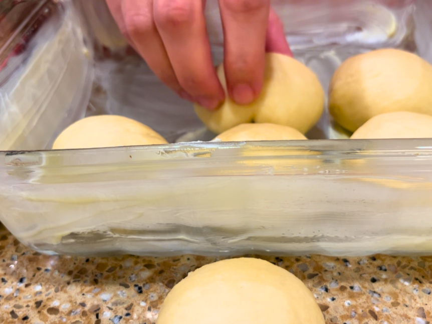 Woman placing dinner roll dough into a greased casserole dish
