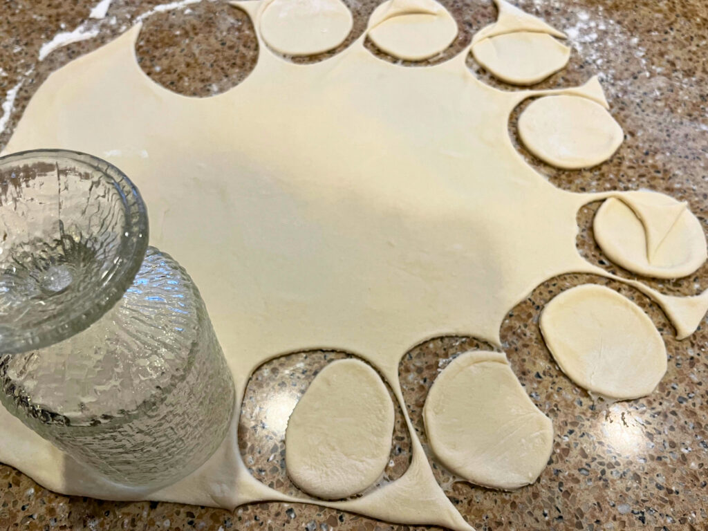 Woman cutting circles with a glass in the pierogi dough