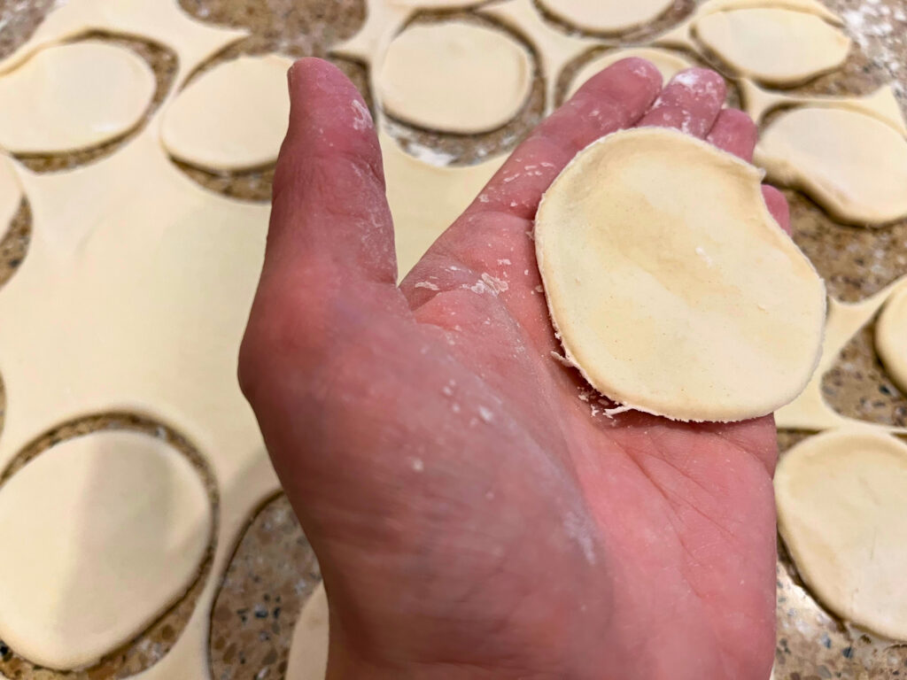 Woman holding a cut circle of dough to make pierogies