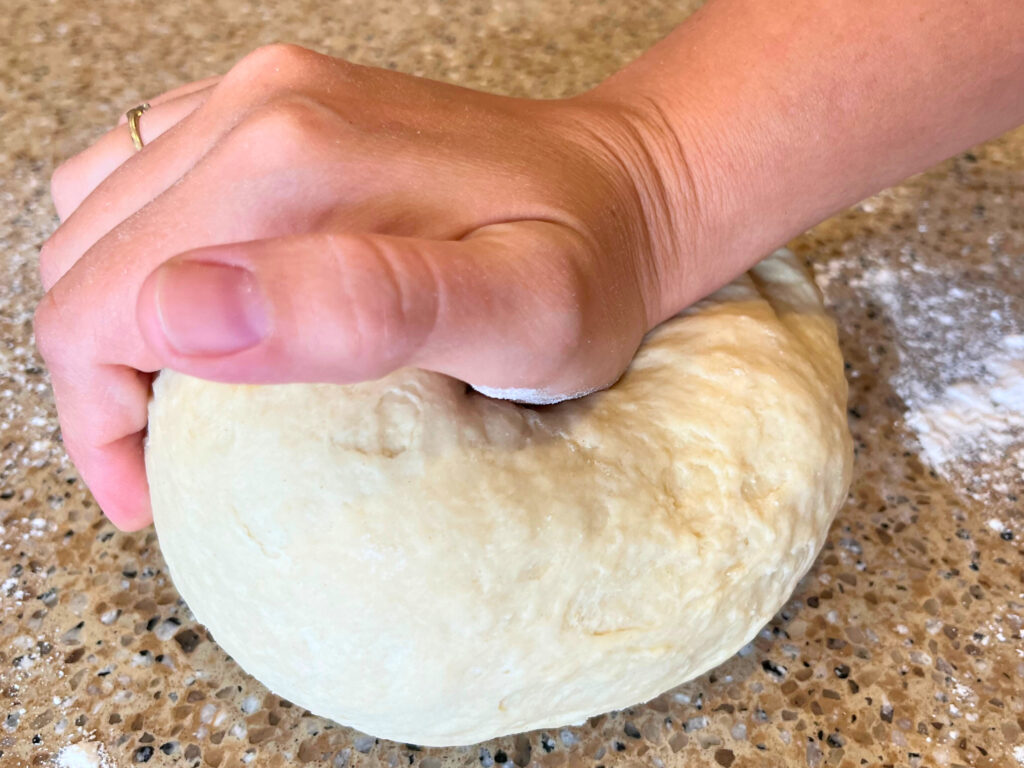 Woman kneading dough on a brown countertop