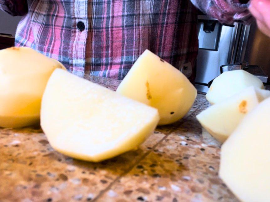 Woman cutting peeled potatoes
