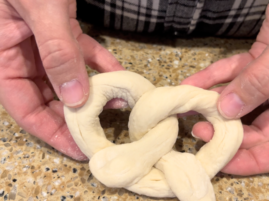 Woman holding up shaped pretzel dough