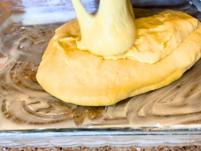 Pouring cake batter into a greased rectangular glass casserole dish.