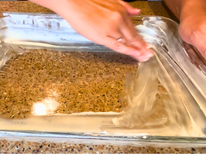 Woman greasing a rectangular casserole dish with butter