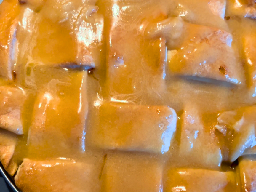 A cooked apple pie with a cooked glaze on top.