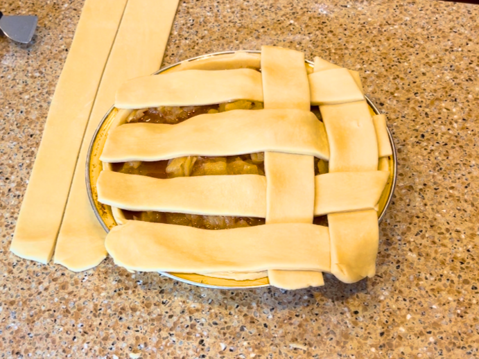 Weaving a lattice top for an apple pie.