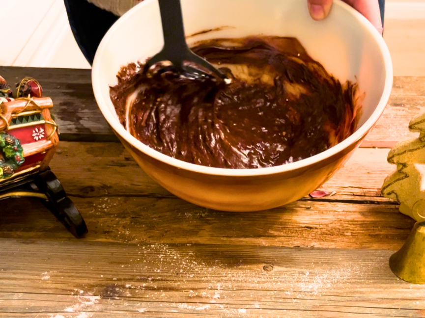 Woman mixing chocolate, sugar, and an egg together.