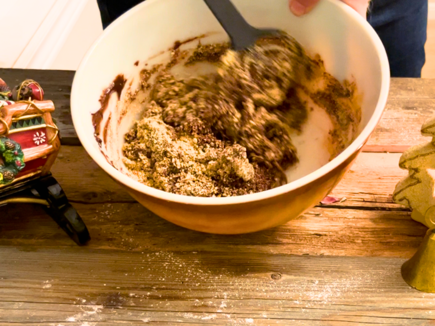 Woman mixing the base for no-bake rich chocolate mint bars in a large bowl.