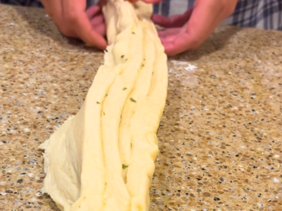 Woman holding strips of dough with garlic butter spread in between.