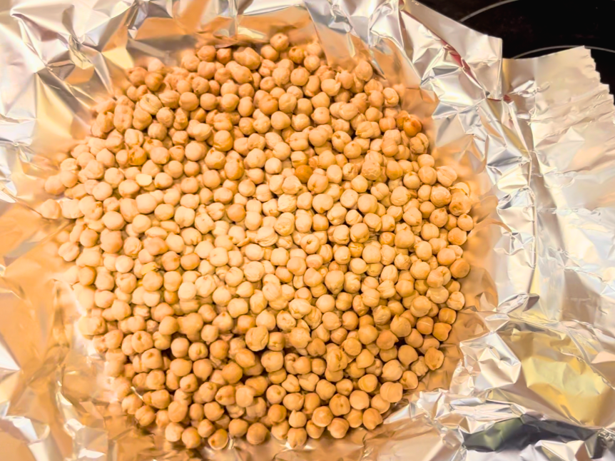 Dried chickpeas on top of aluminum foil, inside an uncooked pie shell.