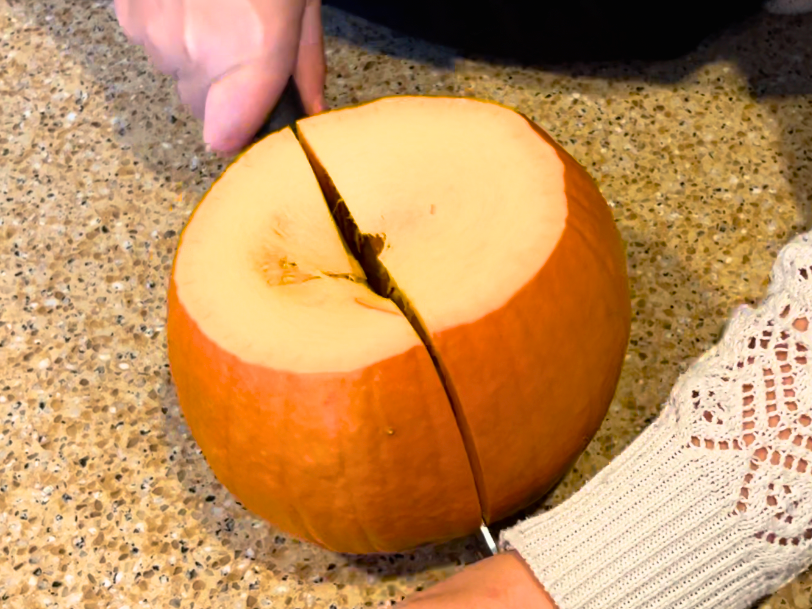 Woman cutting a small pie pumpkin in half