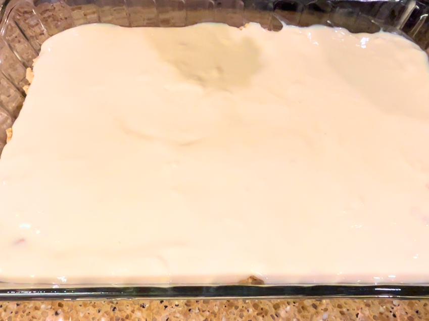 A casserole dish with an uncooked cheesecake mixture