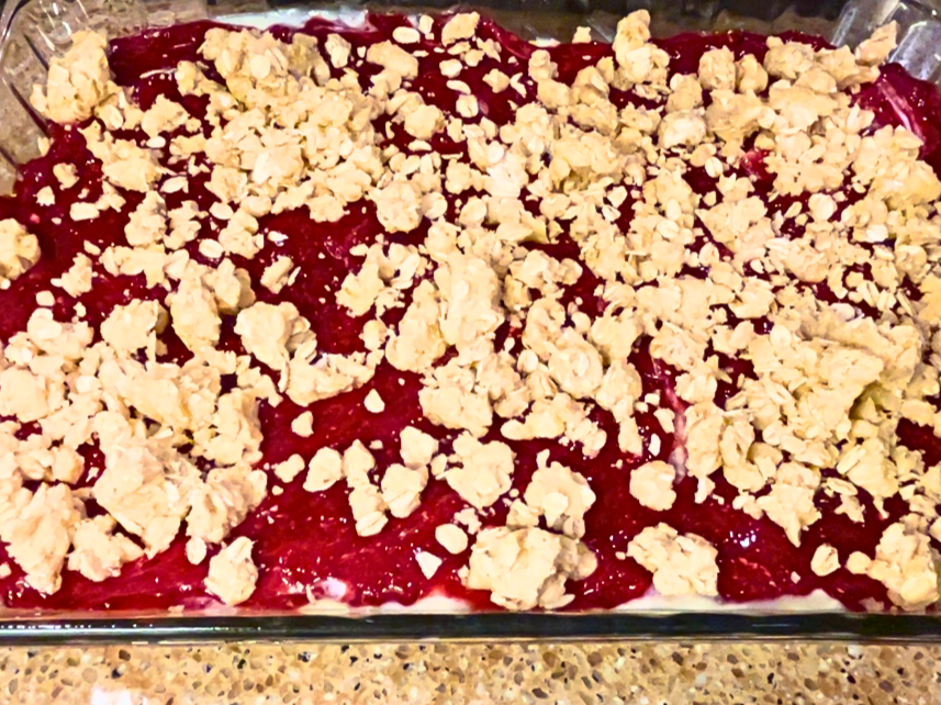 Uncooked cranberry cheesecake bars with a oatmeal crumble on top.