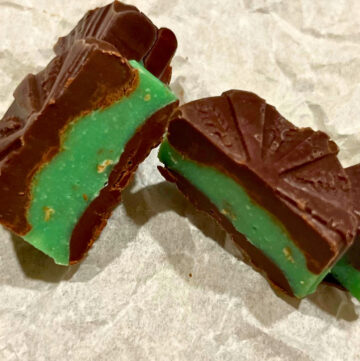 A chocolate mint candy cut in half on a piece of parchment paper.
